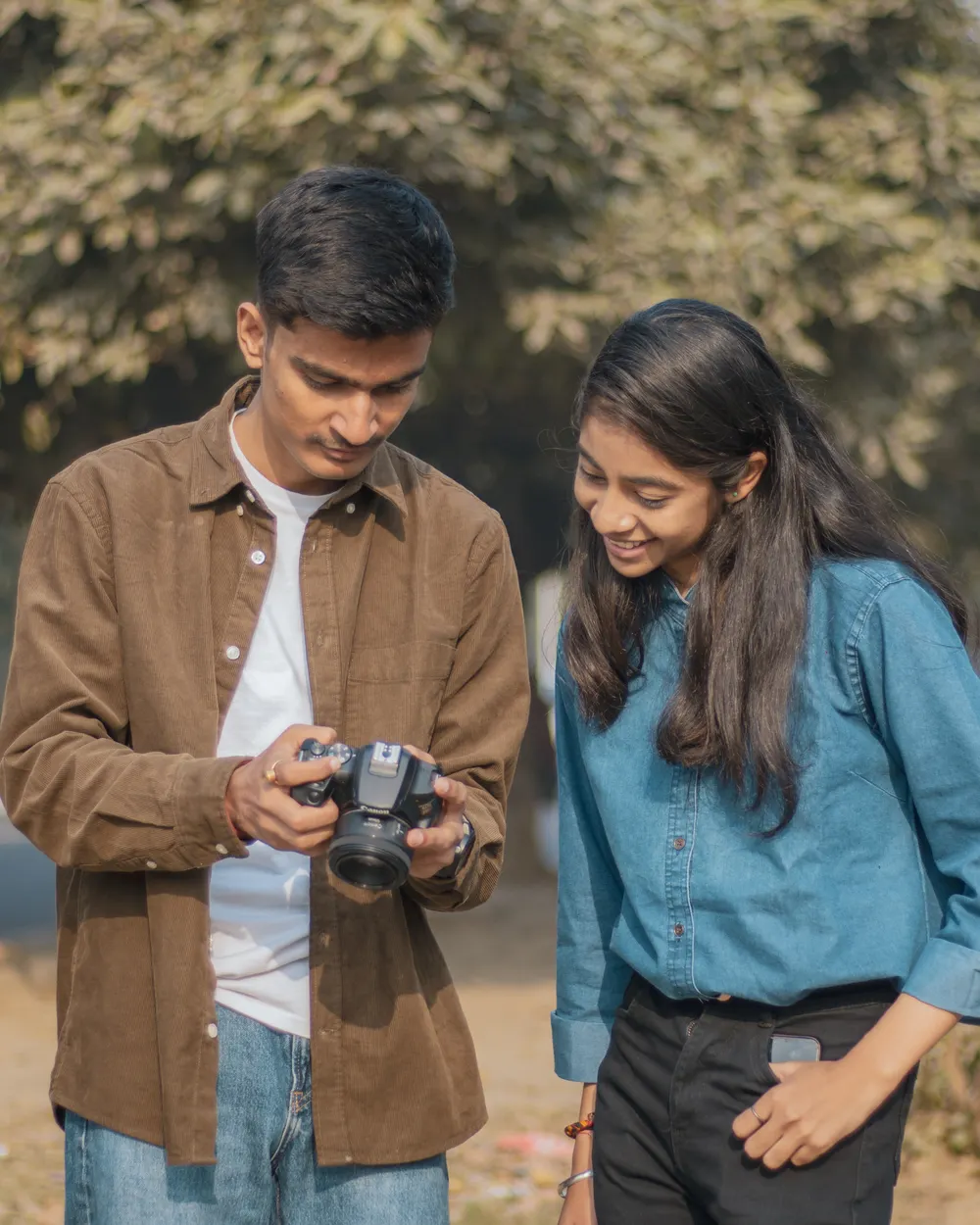 A student showing a friend photos on the back of a camera.